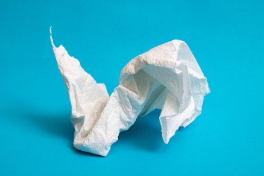 Buruşmuş kağıt peçete mavi arka planda, yakın plan.