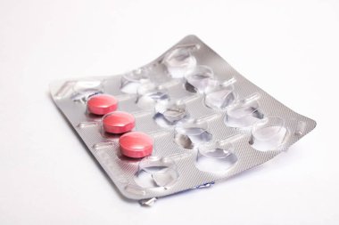 Gri arka planda pakette üç pembe hap. Yakın plan.