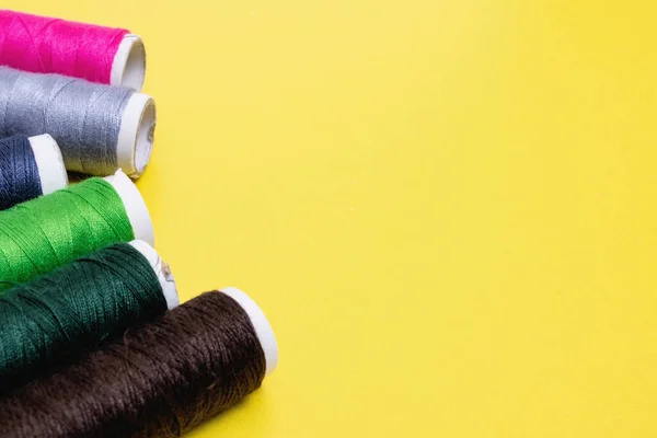 Coils with multicolored threads on a yellow background, copy space