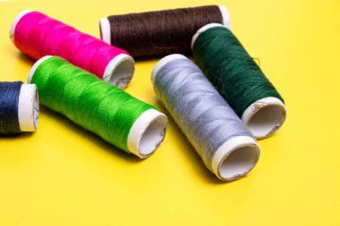 Sarı arkaplanda çok renkli iplikleri olan bobinler yakın plan