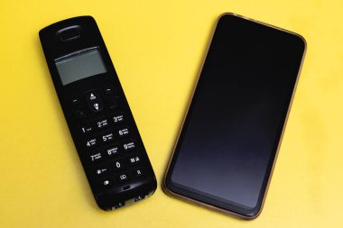 Eski tuşlu telefon ve sarı arka planda modern akıllı telefon.