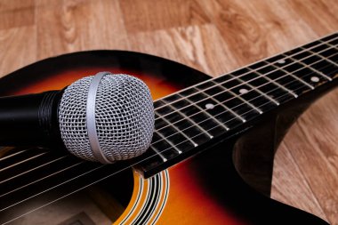 Tahta bir arka planda mikrofon ve gitar, kopyalama alanı
