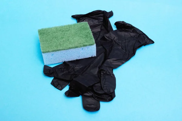 黑色橡胶手套和用于在蓝色背景下洗碗的海绵 — 图库照片