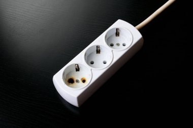 Siyah bir arkaplanda eski yanmış uzatma kablosu.