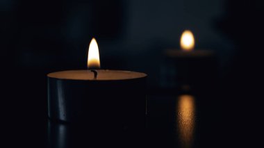 Karanlıkta yansıması olan küçük bir mum alevi