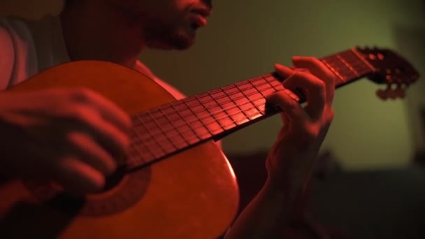 ギター ミュージシャンがリハーサルをする 彼は薄暗い赤信号の部屋にいる — ストック動画