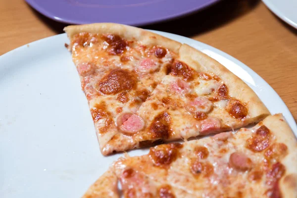 Heiße Pizzascheibe mit schmelzendem Käse auf einem rustikalen Tisch. — Stockfoto
