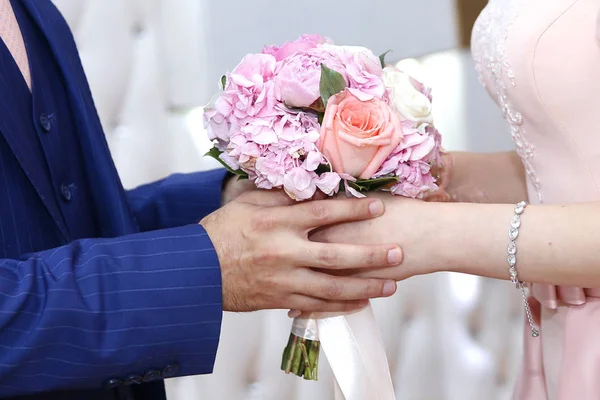 Una novia en un vestido de compromiso blanco con un ramo de novia en la mano es sostenida por su novio — Foto de Stock