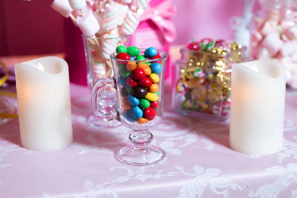Bunte Bonbons. Bunte Süßigkeiten. farbige Bonbons im Glas. runde Schokolade ist sehr farbenfroh. Kerze . — Stockfoto