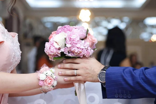 Mãos com flores de noivado, o noivo põe flores de noivado à noiva, vestindo umas flores de noivado, noivo com a noiva. Flores cor de rosa — Fotografia de Stock