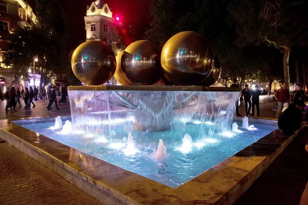 The fountain in the city center. View to crowded street and people in Baku Azerbaijan . night vision of a round park fountain — Stock Photo, Image
