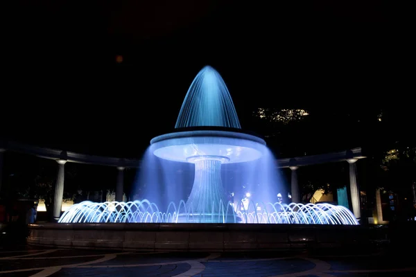 The fountain in the city center. View to crowded street and people in Baku Azerbaijan . night vision of a round park fountain — Stock Photo, Image