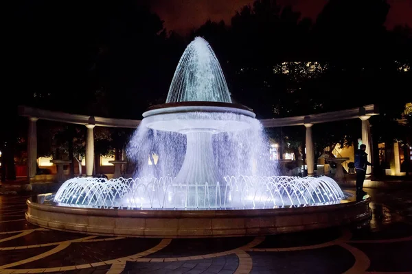 Brunnen in der Innenstadt. Blick auf überfüllte Straßen und Menschen in Baku Azerbaijan. Nachtsicht eines runden Parkbrunnens — Stockfoto