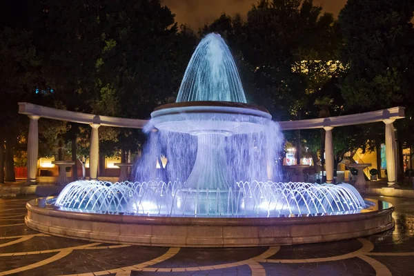 La fontana nel centro della città. Vista sulla strada affollata e la gente in Baku Azerbaijan. visione notturna di un parco rotondo Fontana piazza — Foto Stock