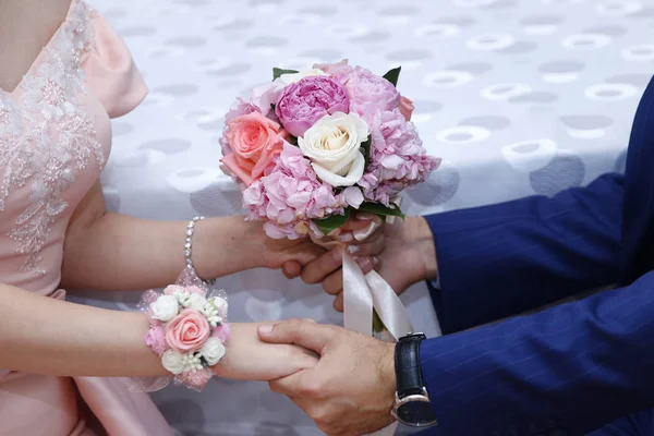 Mãos com flores de noivado, o noivo põe flores de noivado à noiva, vestindo umas flores de noivado, noivo com a noiva. Flores cor de rosa — Fotografia de Stock