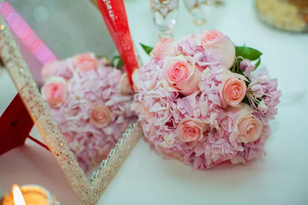 Bouquet da sposa di rose rosa e fedi nuziali su un tavolo di legno. Ricevuto. Il concetto di matrimonio, festa, amore e famiglia e anelli — Foto Stock