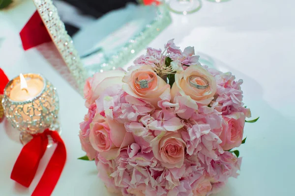 Hochzeitsstrauß aus rosa Rosen und Trauringen auf einem Holztisch. Kopierraum. das Konzept einer Hochzeit, Party, Liebe und Familie und Ringe — Stockfoto