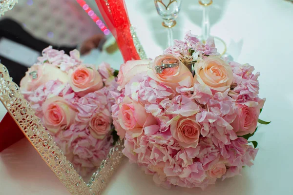 Bruiloft boeket van roze rozen en trouwringen op een houten tafel. Kopieer ruimte. Het concept van een bruiloft, feest, liefde en familie en ringen — Stockfoto