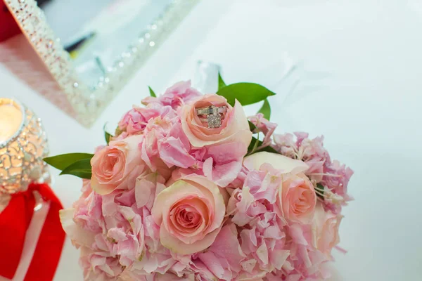 Hochzeitsstrauß aus rosa Rosen und Trauringen auf einem Holztisch. Kopierraum. das Konzept einer Hochzeit, Party, Liebe und Familie und Ringe — Stockfoto