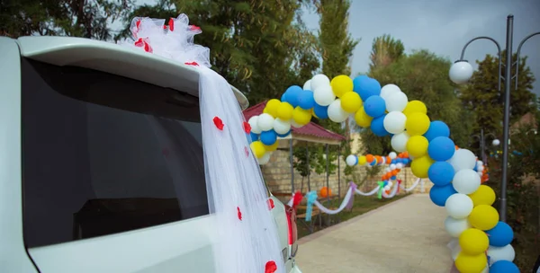 Auf einer Leinwand Blütenblatt Tüll Auto. der mit Luftballons geschmückte Brautweg. verdrehte weiße, gelbe, Himmelsballons — Stockfoto