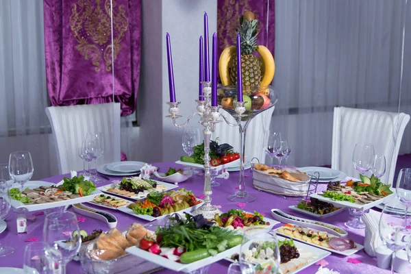 Элегантный обеденный стол. Свадебный стол украшен свечами, сервируется со столовыми приборами и посудой и покрыт скатертью. Розовая скатерть. Белые стулья. Белый свадебный стол. Стол украшен — стоковое фото
