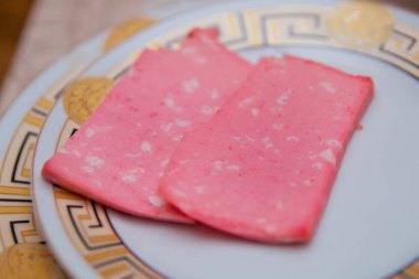 Doğranmış sosis tabakta. Dilimlenmiş Sosis füme kıyılmış et üzerinden bir cam levha masada yatıyor. Yakın çekim, seçici odak.