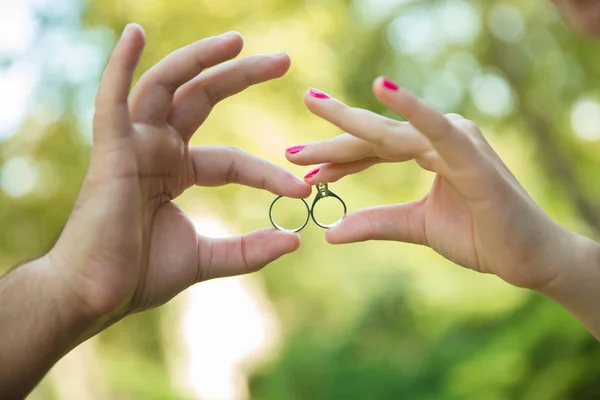 Flickan och pojken håller ringen i sina händer. På den gröna bakgrunden. kärlekshistoria — Stockfoto