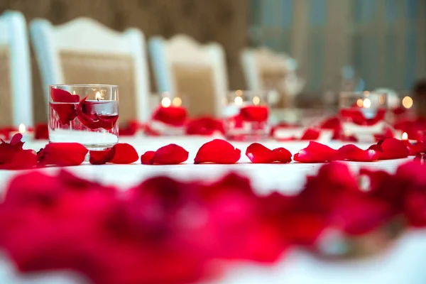 Красивые романтические красные свечи с лепестками цветов. Лепестки цветов, свечи и стекло  . — стоковое фото