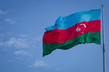 Azerbaycan Ulusal bayrak mavi gökyüzü arka plan üzerinde. Azerbaycan bayrağı bulutlu gökyüzü karşı rüzgarda sallayarak. Azerbaycan bayrağı kumaş dokusu