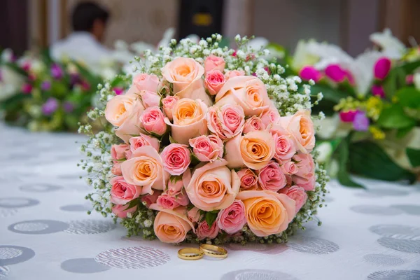 Bruids boeket met oranje en roze rozen van verschillende grootte met handvat op witte achtergrond. Romantische bruiloft boeket met prachtige bloemen. Twee ringen vertegenwoordigen de betekenis van gevoel liefde — Stockfoto