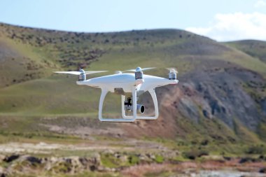 Drone dört helikopter gökyüzü üzerinde yüksek çözünürlüklü dijital kamera ile. Beyaz drone ile dijital fotoğraf makinesi dağ Drone ile yüksek çözünürlüklü dijital fotoğraf makinesi üzerinde gökyüzünde uçan.
