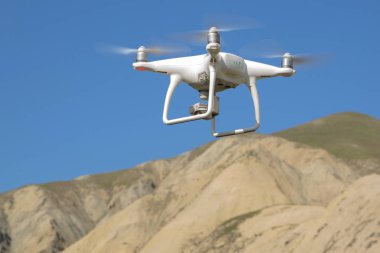 Drone dört helikopter gökyüzü üzerinde yüksek çözünürlüklü dijital kamera ile. Beyaz drone ile dijital fotoğraf makinesi dağ Drone ile yüksek çözünürlüklü dijital fotoğraf makinesi üzerinde gökyüzünde uçan.