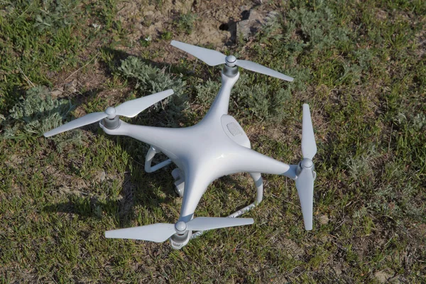 Λευκό drone με ψηφιακή φωτογραφική μηχανή που πετούν στον ουρανό πάνω από το βουνό Drone με κάμερα υψηλής ανάλυσης ψηφιακή. Drone με κάμερα στο γρασίδι ετοιμάζεται να πετάξει . — Φωτογραφία Αρχείου