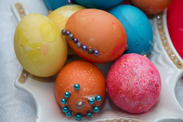 Пасхальные яйца ручной работы на винтажной платформе. Многие разноцветные пасхальные яйца на белой пластине помещены кучей и мраморным фоном. Изображение нескольких цветных яиц, помещенных на тарелку  . — стоковое фото