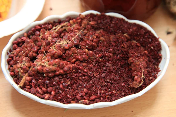 Dried sumac seasoning in a wooden bowl, top view. a handful of r — Stock Photo, Image