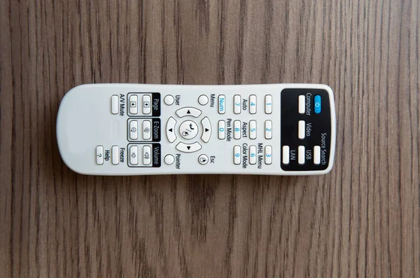Remote controller . White projector System REMOTE Control wooden background. Projector console on a wooden table .