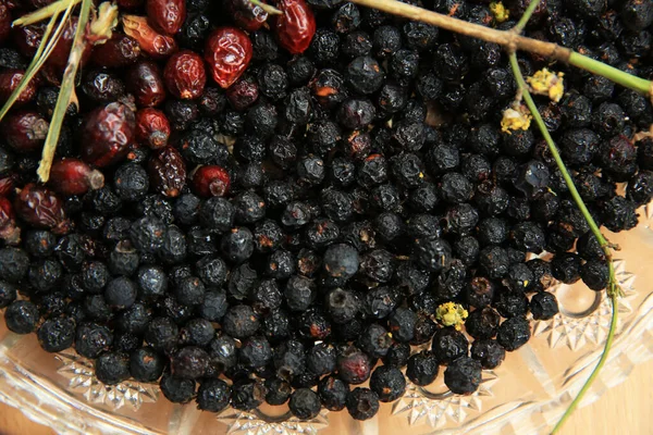 Hawthorn na dřevěném venkovském stole pozadí. V kyčlích růží rostly psí plody. Černé bobule chokeberry jam . — Stock fotografie
