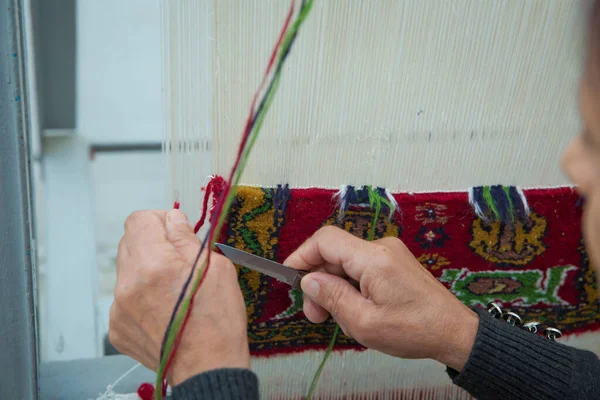 weaving and manufacturing of handmade carpets closeup. women\'s hands weave a carpet . Woman hands weaving carpet .