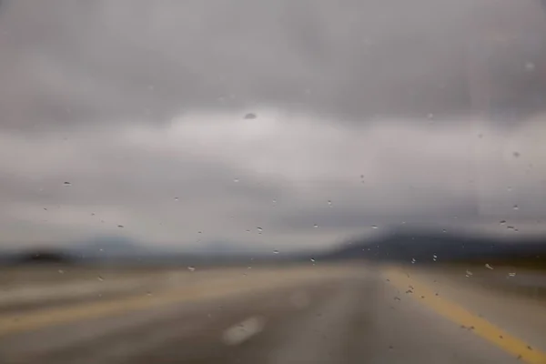 Queda de chuva em vidro da estrada de carro com nevoeiro ou névoa na natureza verde. A água cai no vidro do carro. gotas de chuva — Fotografia de Stock