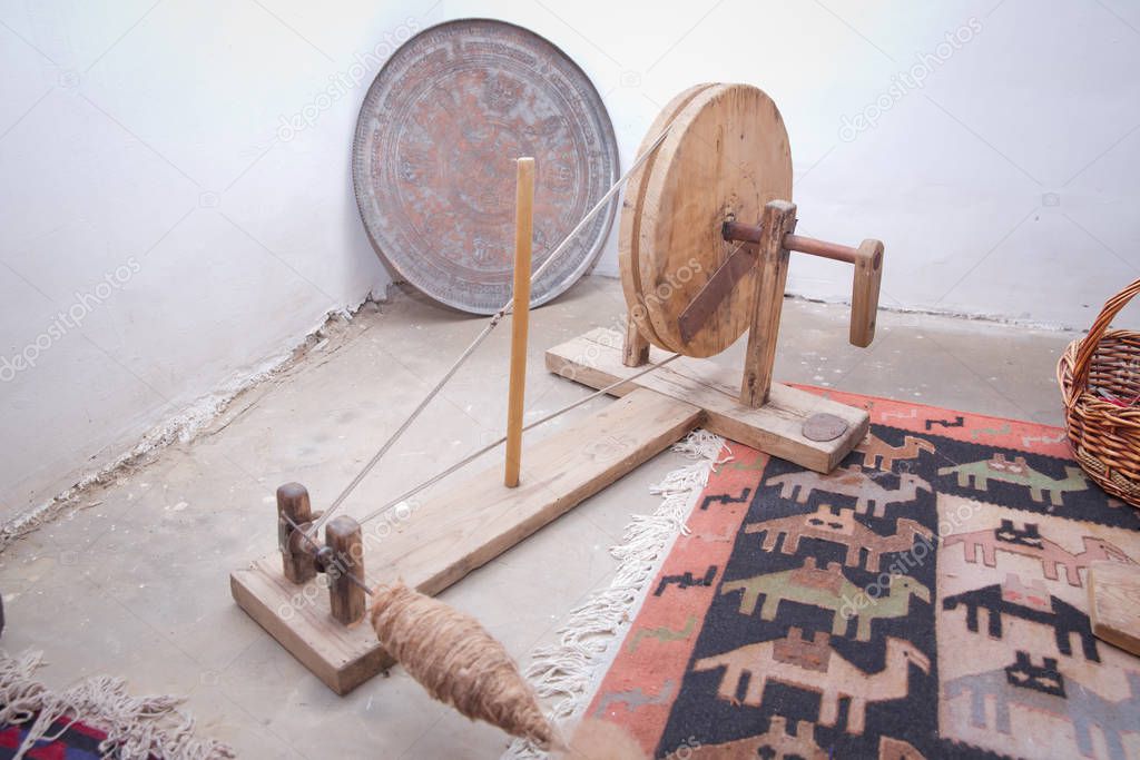 the old wooden wool winding machine with materials .Old fashioned wooden distaff, spindle, spinning wheel . wool thread in the basket . Old Azerbaijan spinning wheel for wool .