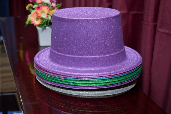 Цветные волшебные шляпы. Розовая металлическая шляпа. Фиолетовая шляпа фокусника на изолированном красном фоне  . — стоковое фото