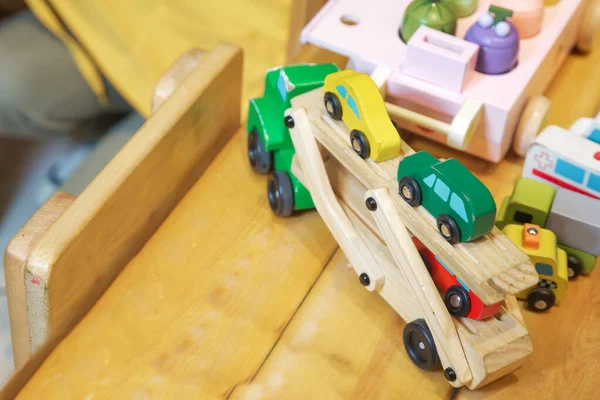 Educational toys for little kids. Train on the wooden table, with white wooden in the background. Baby. Fun. Happy Childhood. Close-up of a wooden toy truck with a painted on the wooden table.