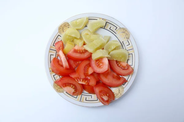 Plate of vegetable salad with fresh tomatoes and cucumbers on wooden background, top view