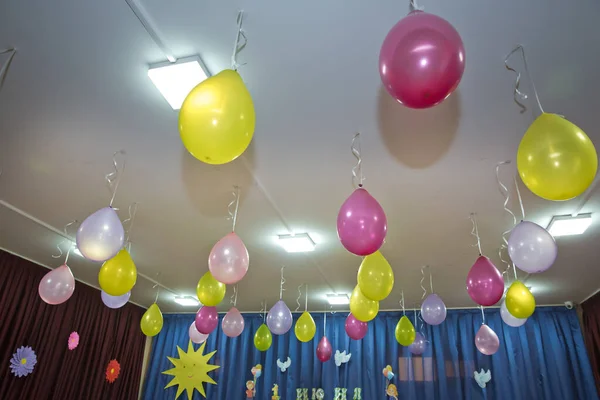 Pink and yellow balloons float on the white ceiling in the room for the party. Wedding or children birthday party decoration interior. Helium balloons.