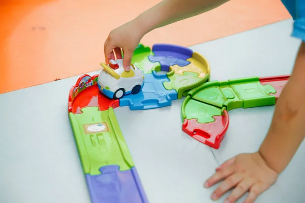 Zbliżenie ręki dzieciaka bawiącego się zabawkowym samochodem. Dziecko bawi się samochodami na kolei zabawek . — Zdjęcie stockowe