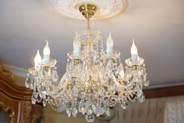 The lamp in the beautiful room .Brass chandelier with crystal. Chandelier ceiling lights . Chandelier Lamp beautiful luxury expensive chandelier hanging under ceiling .