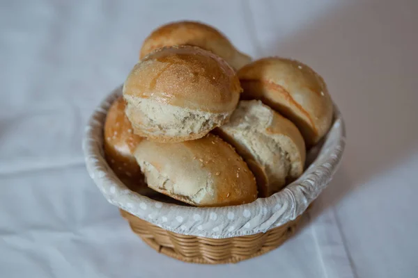 Koszyk z ciasta. Słodkie bułeczki z makiem w wiklinowym koszu, wokół chleba żytniego z nasionami sezamu . — Zdjęcie stockowe