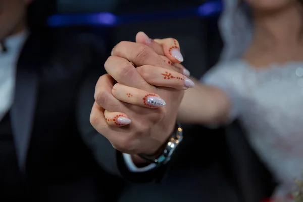 Brud- och brudgumshänder med vigselringar och brudklänning. Brudgummens händer med vigselringar. Bröllopspar som håller varandra i handen . — Stockfoto