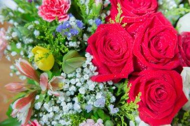 Kırmızı çiçek resmi buketin içinde. Çiçeğin taç yaprağı. Taze kırmızı, beyaz, turuncu güller. Bir buket çok renkli gül. .