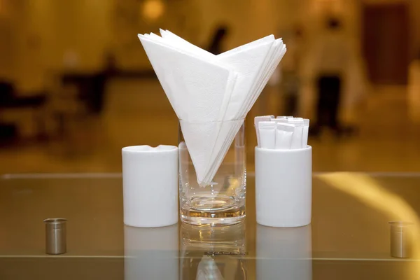 Λευκό χαρτοπετσέτες σε μεταλλική χαρτοπετσέτα, μπαχαρικά αλάτι και πιπέρι σε ένα ξύλινο τραπέζι, πανοραμική θέα. οδοντογλυφίδα. Τραπέζι σε καφετέρια ή εστιατόριο. — Φωτογραφία Αρχείου